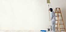 עובד צובע קיר פנימי בעזרת רולר וסולם