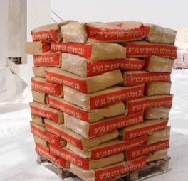 שקי מלט תעשייתיים מסודרים ומחוברים בפלסטיק, מוכנים להובלה