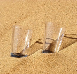 שתי כוסות זכוכית מעבדה עם אבקה לבנה מונחות על קרקע חולית