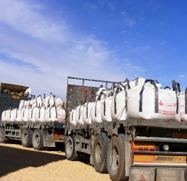 משאית שטוחה המובילה מיכלי אחסון לבנים גדולים תחת שמיים כחולים